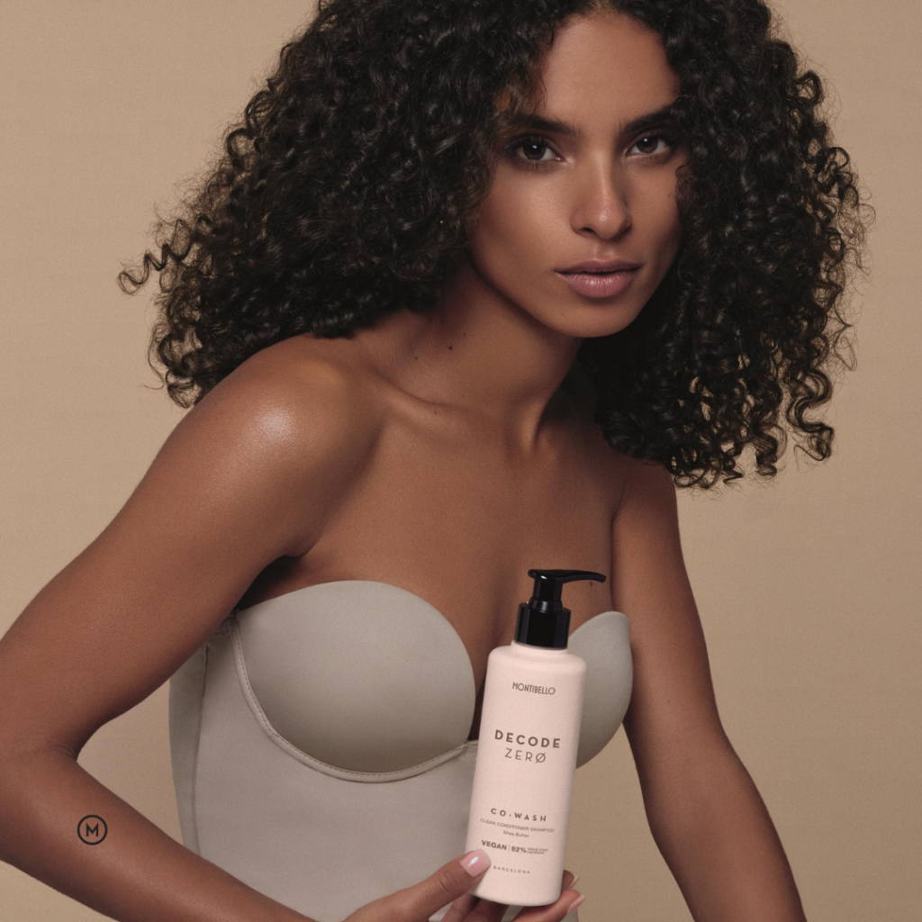 modelka z kręconymi włosami trzymająca produkt szampon Co-wash